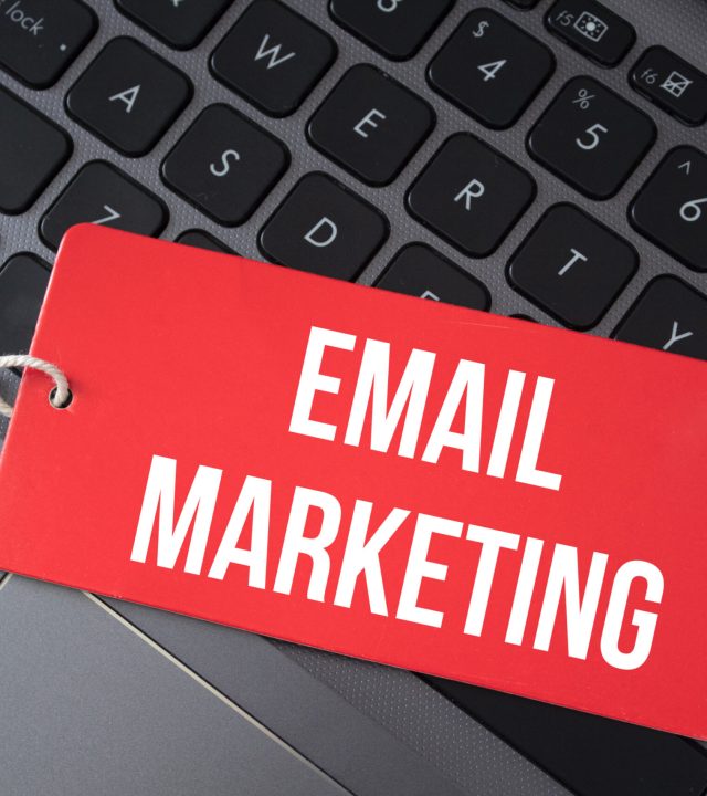 Top view of red paper and the text email marketing on a laptop background.